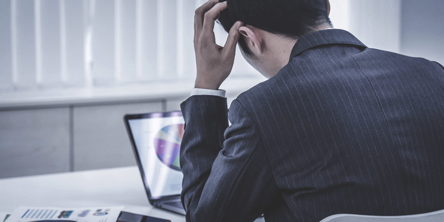 PCを前に頭を抱える男性