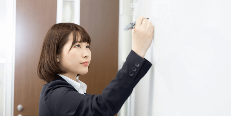 PPAP導入時の注意点の研修のためにホワイトボードに書き込む女性社員
