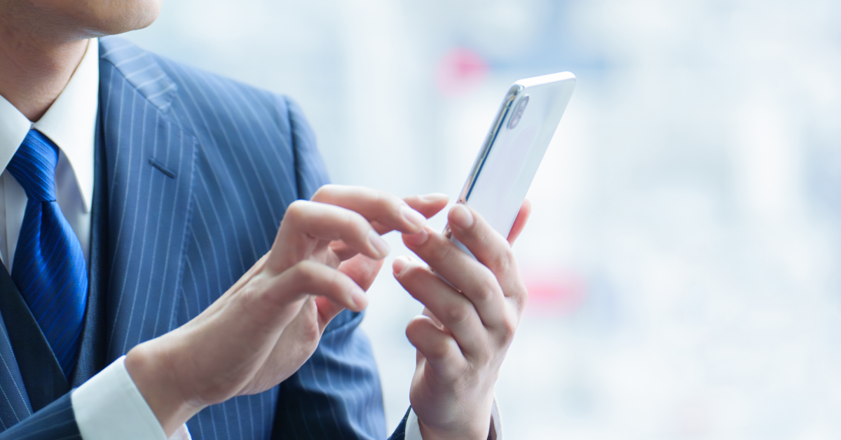 ビジネススーツ人物とスマホ操作手元のイメージ画像