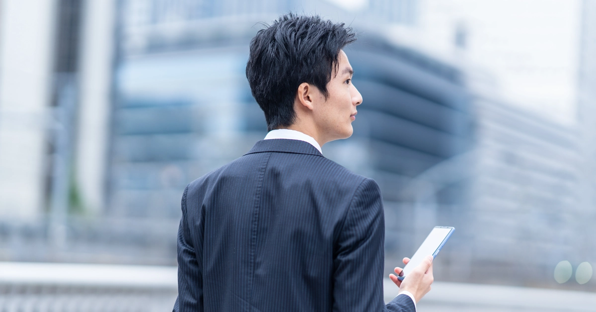 男性が外出先でスマホを持っている画像