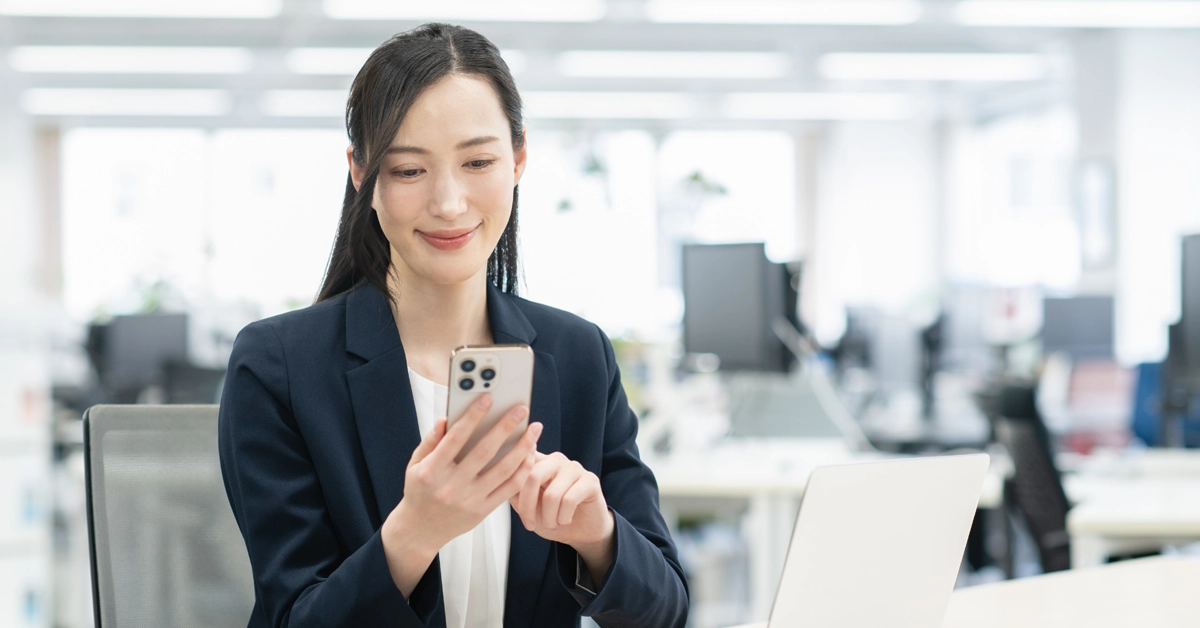 オフィスでスマホを操作している女性の画像