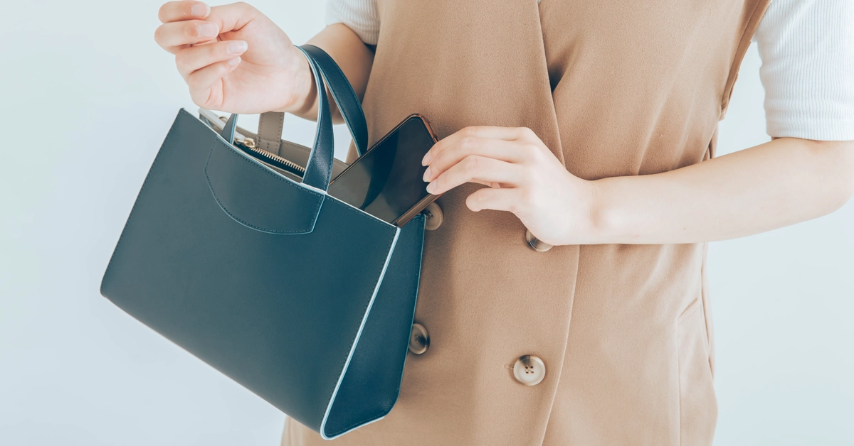 バッグからスマホを取り出す女性の画像