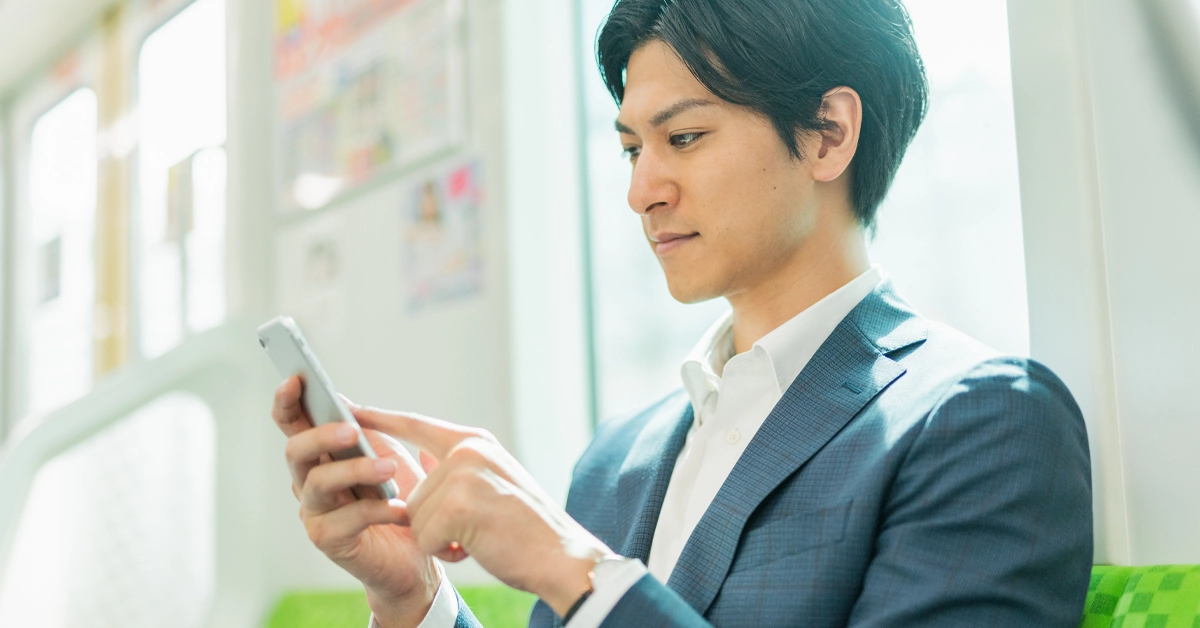 電車内でスマホを操作する男性の画像