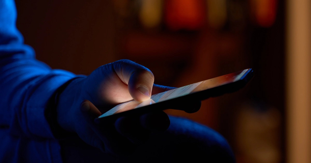暗い部屋でスマホを操作している手元の画像