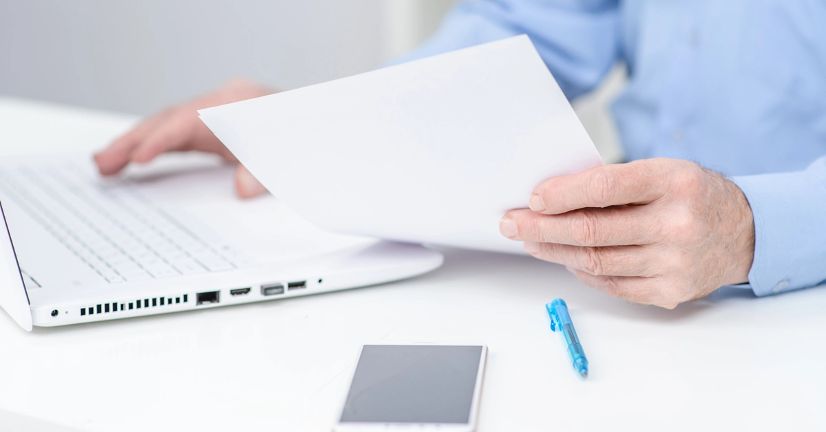 オフィスで書類を持つ手とスマホの画像