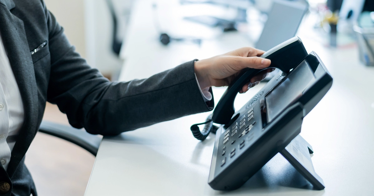 固定電話をかけようとしているビジネスパーソンの画像